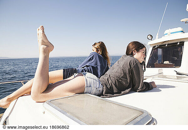 Women lying together on boat deck at vacation