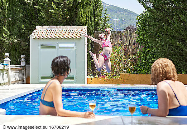 Women on vacation in a swimming pool. Children play in front of them.