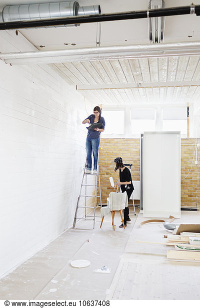 Women painting wooden wall