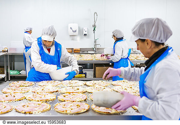 Women preparing pizzas in pizza company