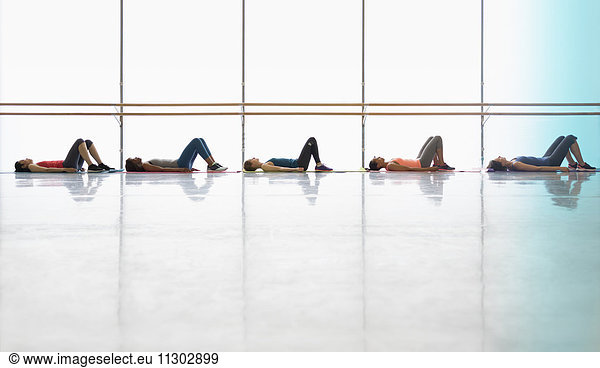 Women resting laying on yoga mats in exercise class gym studio
