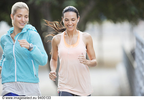 Women running through city streets together