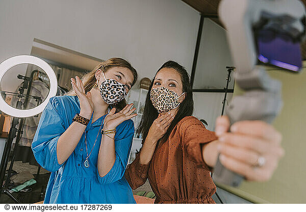 Women showing leopard printed face masks while vlogging at home