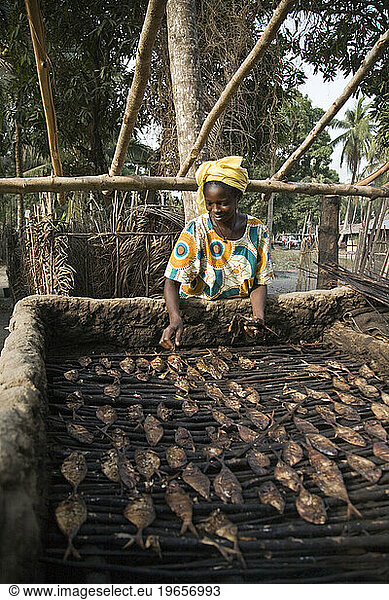 Women smoke drying fish in Sierra Leonean fishing village of Sulima