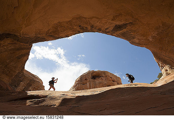 Women stand inside a sandstone rock arch  McInnis Canyons  Colorado