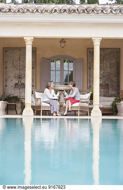 Women toasting each other by swimming pool