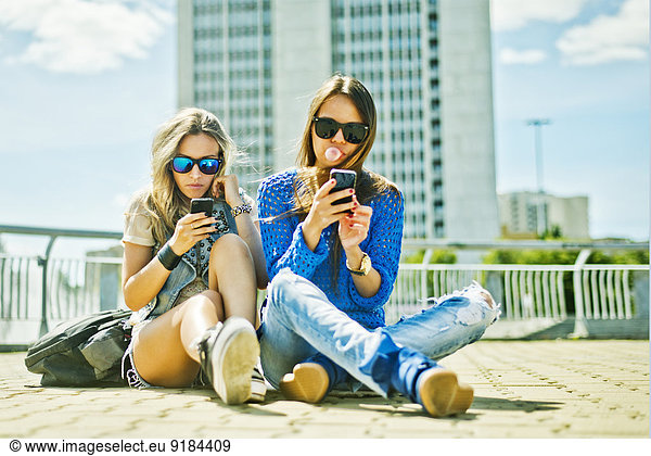 Women using cell phones on city street