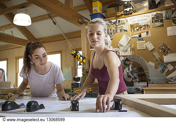 Women with blueprint working in workshop