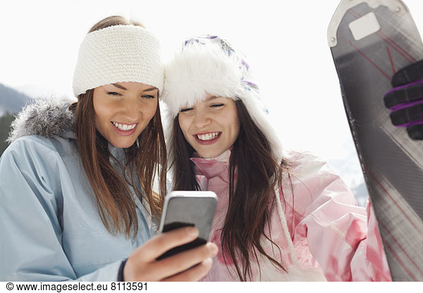 Women with skis text messaging with cell phone