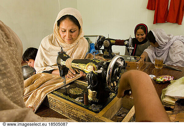 Women work together sewing in a Kabul work room.