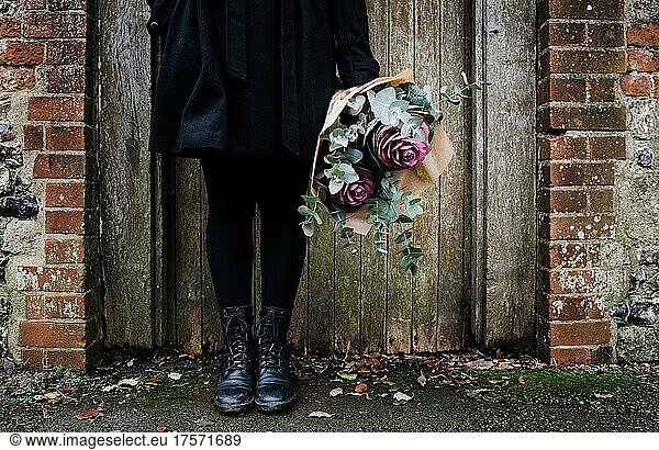 womens boots by an old English door with a bouquet of flowers