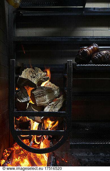 Wood burning grill with logs smoke & fire smoking meat at a restaurant