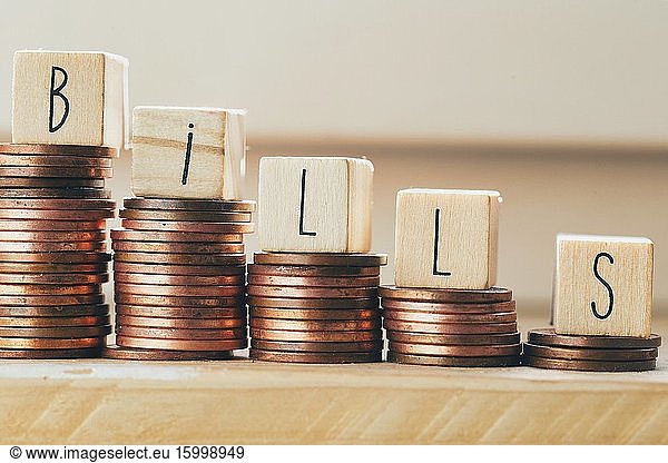Wooden blocks with the word bills and pile of coins  money climbing stairs Payment of taxes and of debt to the state. Concept of financial crisis and problems. Risk management. Debt exemption. loan closeup.