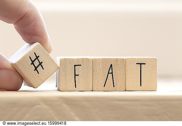 Wooden cubes with a hashtag and the word Fat  social media and health concept background.