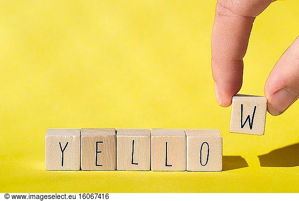 Wooden cubes with the word Yellow on Yellow background Cheerful summer concept colorful retro design close-up.