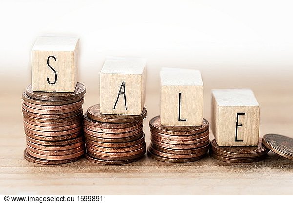 Wooden cubes with word SALE and money climbing stairs background. pile of coins Business concept close-up.