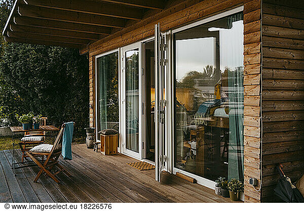 Wooden porch with chairs by glass door outside house