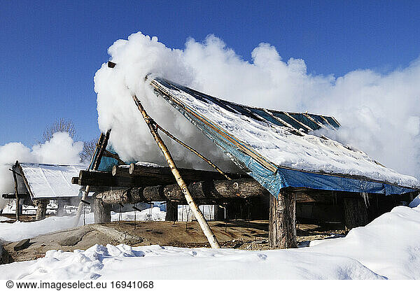 Wooden shack covered with clouds in snow.