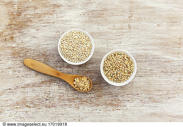 Wooden spoon and two bowls of barley flakes