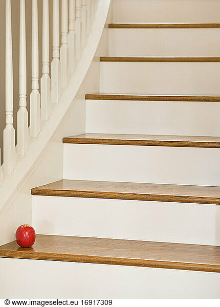 Wooden staircase with banister and red apple.