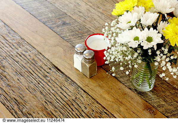 Wooden table in coffee shop with flower arrangement and salt & pepper