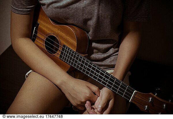 Wooden ukulele in hands of girl  close-up