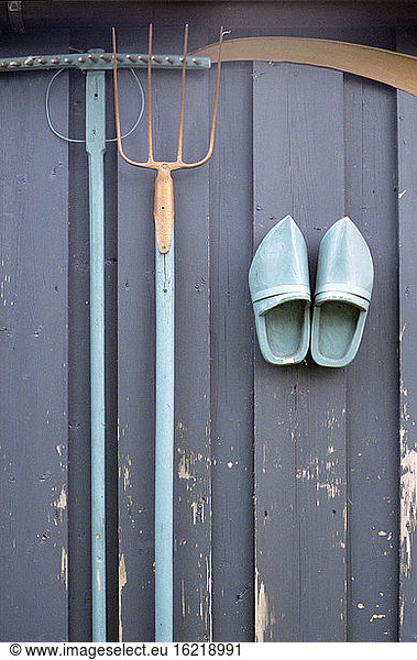 Wooden wall with gardening tools and shoes