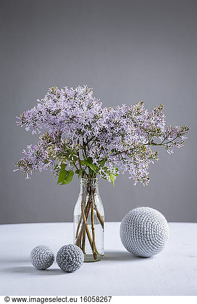 Wool spheres and bottle with blooming lilacs