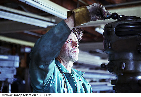 Worker adjusting machinery in workshop