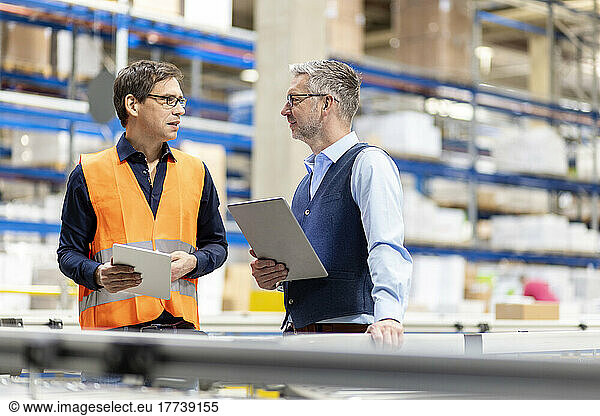 Worker and manager with tablet PC discussing together in warehouse