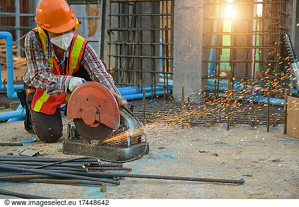 Worker cut steel with cutting machine circular disc cuts off par