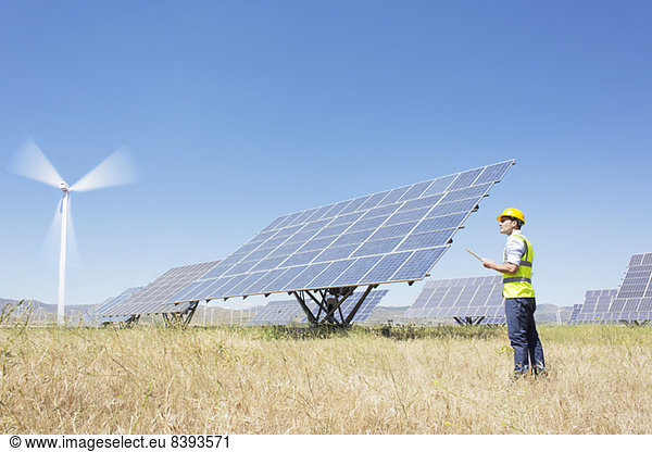 Worker examining solar panels in rural landscape