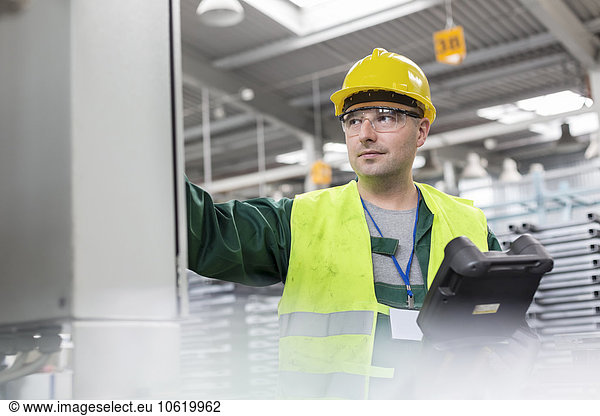 Worker in protective workwear at control panel in factory