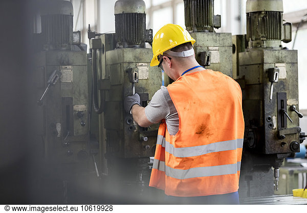 Worker in protective workwear operating machinery in factory