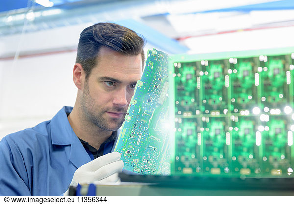 Worker inspecting circuit boards in circuit board assembly factory