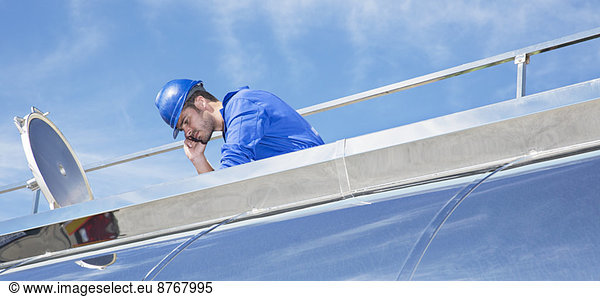 Worker on platform above stainless steel milk tanker