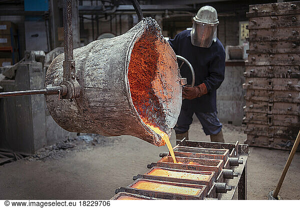 Worker pouring ingots of brass in brass foundry