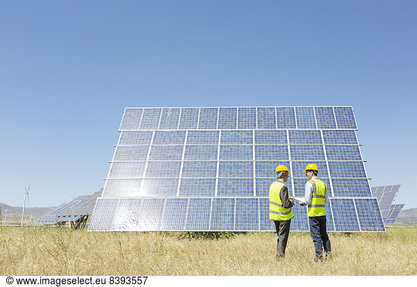 Workers examining solar panel in rural landscape