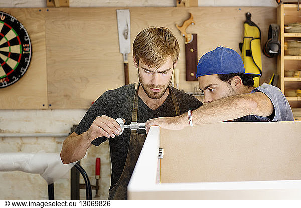 Workers measuring wood while working in workshop