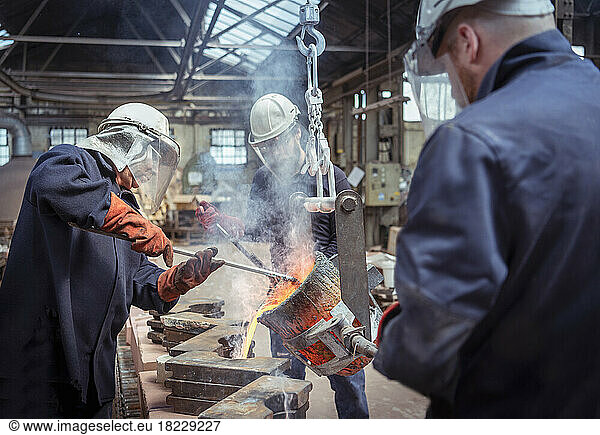 Workers pouring molten brass in brass foundry