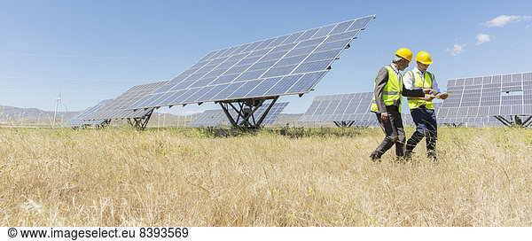 Workers walking by solar panels in rural landscape