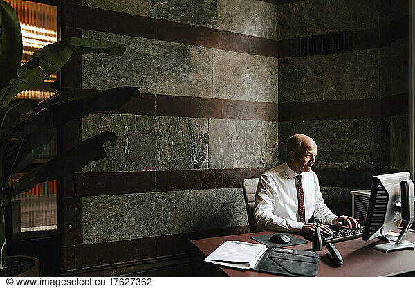 Working senior businessman using computer at law office