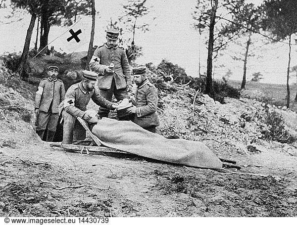 World War I 1914-1918: Wounded German soldier on a stretcher being treated behind the trenches by a field medical team displaying the symbol of the Red Cross  1915. Medicine First Aid Warfare Casualty