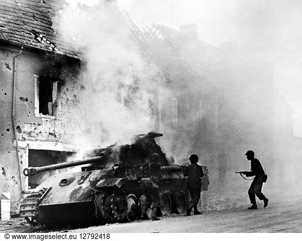 WORLD WAR II: NORMANDY. A burning German Giant Tiger tank surrounded by American soldiers in a village on the Perrier front in Normanday,  France,  29 July 1944.