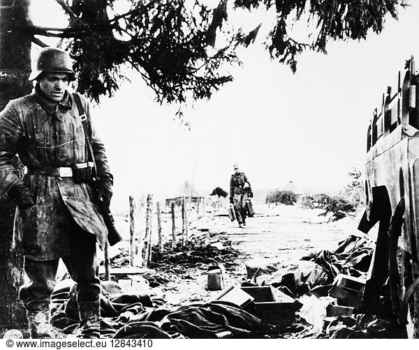 WORLD WAR II: BELGIUM  1944. A German soldier examines litter left behind by American soldiers in territory taken by the Germans in the Belgian breakthrough  December 1944.