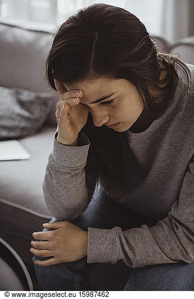 Worried woman sitting on sofa at home