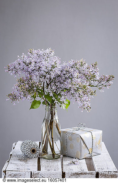 Wrapped gift and bottle with blooming lilacs