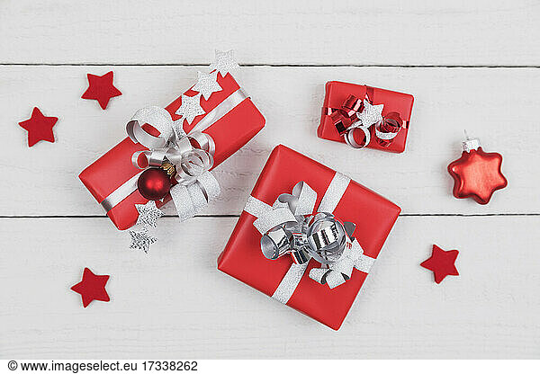 Wrapped presents and star shaped Christmas decorations flat laid on white wooden surface