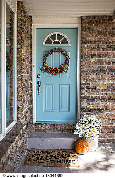 Wreath hanging on door with pumpkin in front of house during Halloween