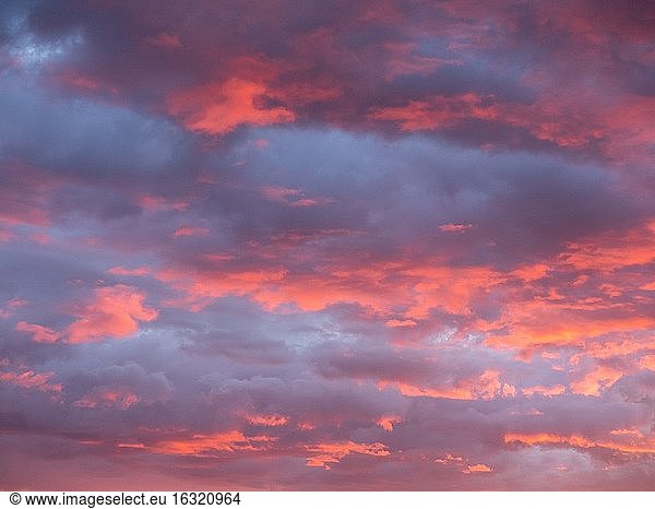 Wunderschöne rote und orangefarbene Wolken bei Sonnenuntergang vor einem blauen Himmel.